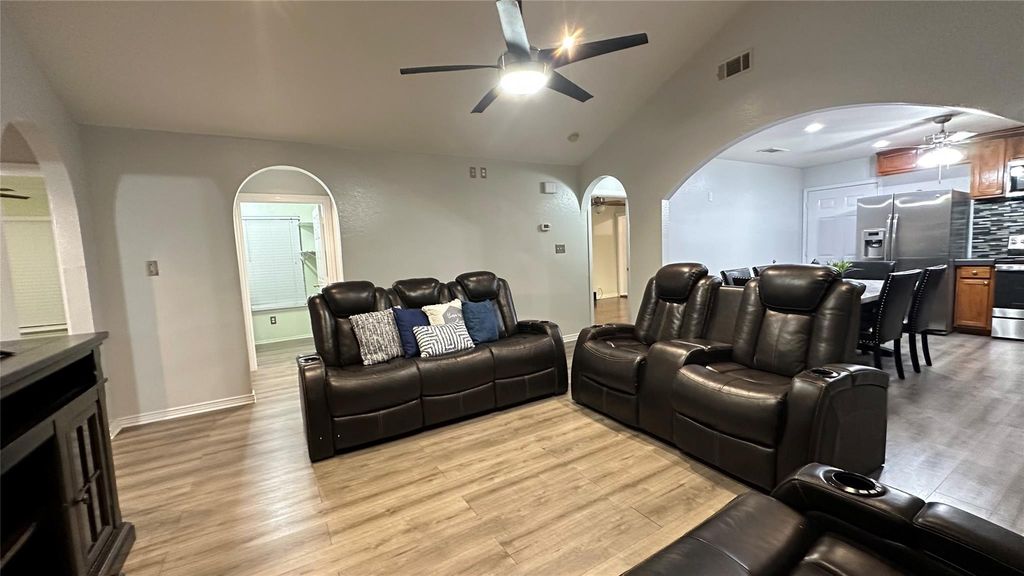 Home theater room featuring arched walkways, a ceiling fan, light wood-style floors, and high vaulted ceiling