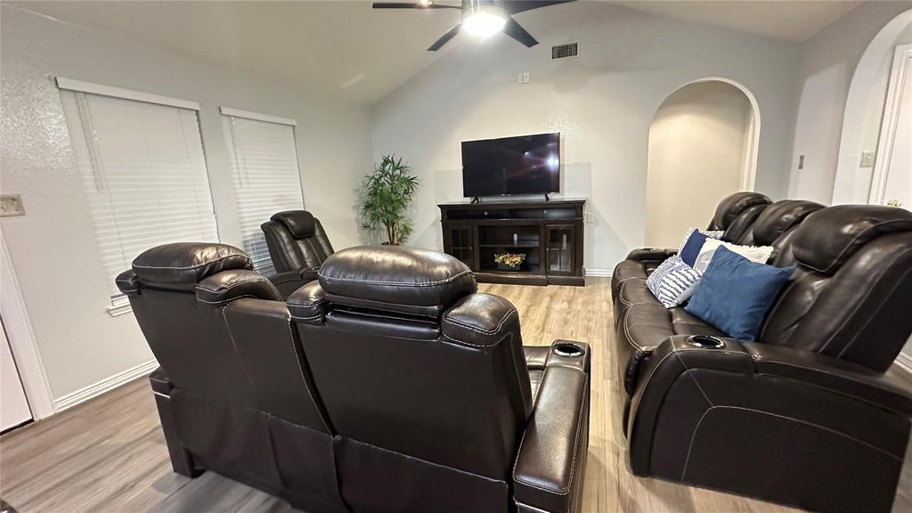 Living area with lofted ceiling, light wood finished floors, and a ceiling fan