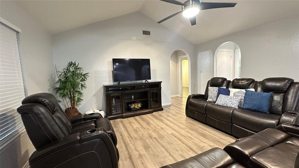 Living area featuring lofted ceiling, wood finished floors, arched walkways, and ceiling fan