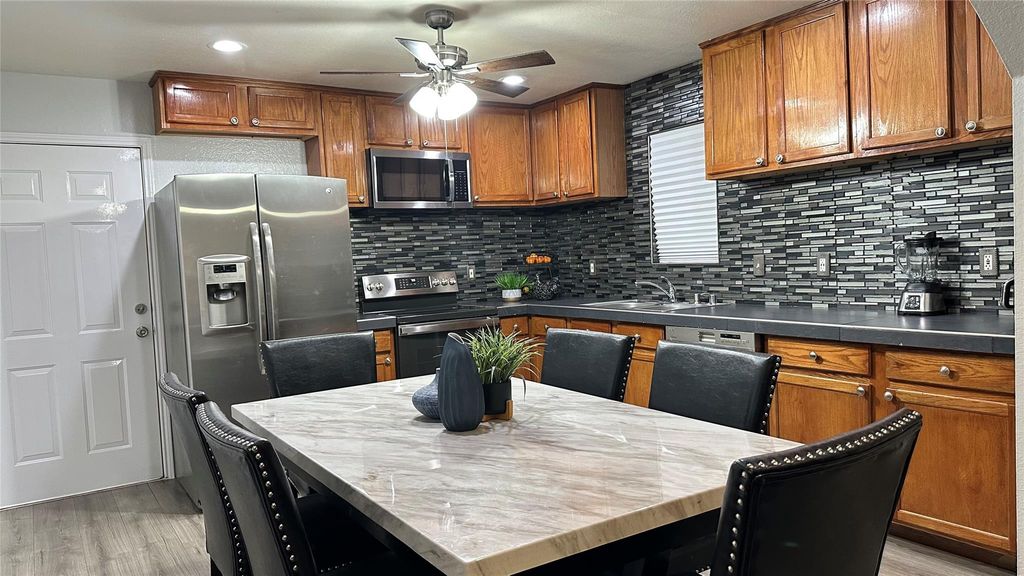 Kitchen with brown cabinetry, decorative backsplash, and light wood-type flooring