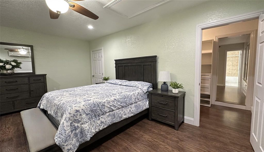 Bedroom featuring a textured wall, dark wood-style floors, a textured ceiling, and a ceiling fan