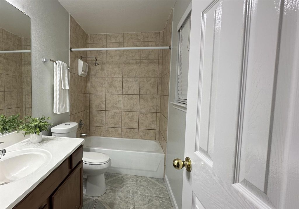 Bathroom featuring vanity, bathing tub / shower combination, a textured wall, and light tile patterned floors