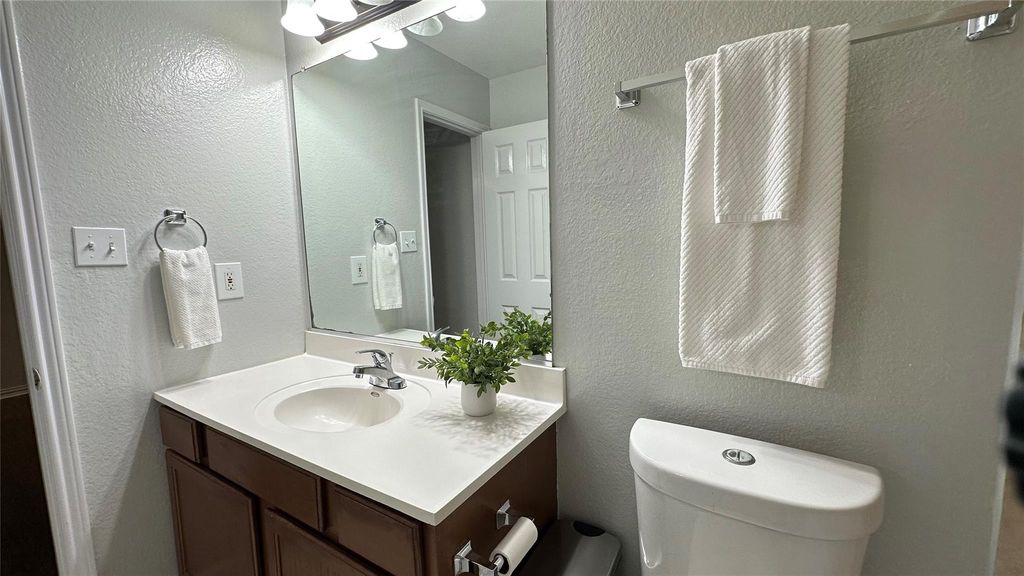 Half bathroom featuring a textured wall and vanity