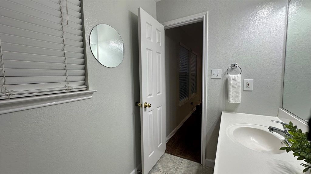 Bathroom with a textured wall, vanity, and light tile patterned flooring