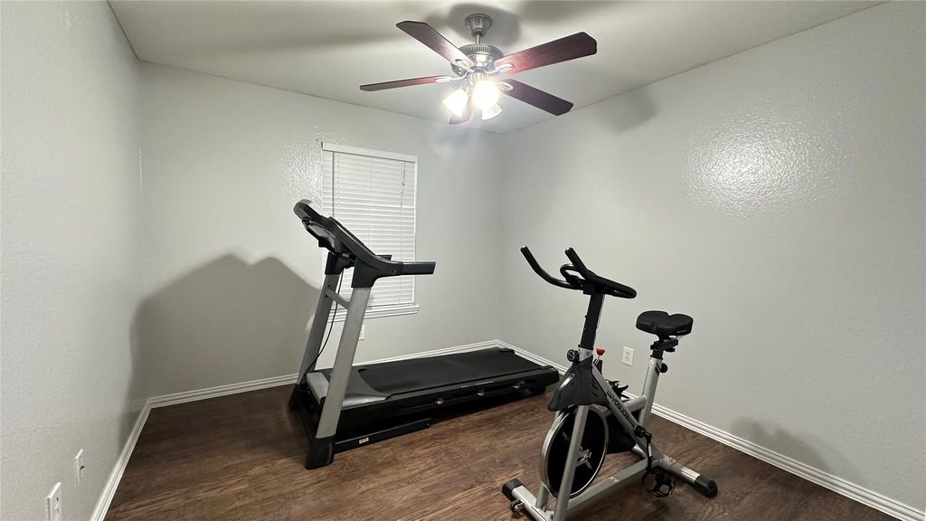 Workout room with dark wood finished floors and a ceiling fan