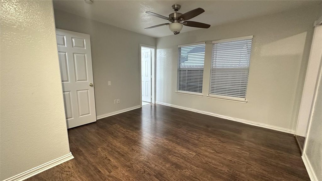 Unfurnished bedroom featuring dark wood finished floors, ceiling fan, and a textured wall