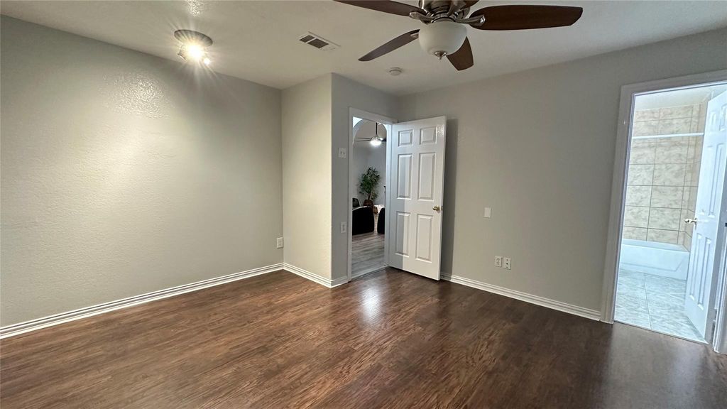 Unfurnished bedroom with dark wood-type flooring, a ceiling fan, and ensuite bath