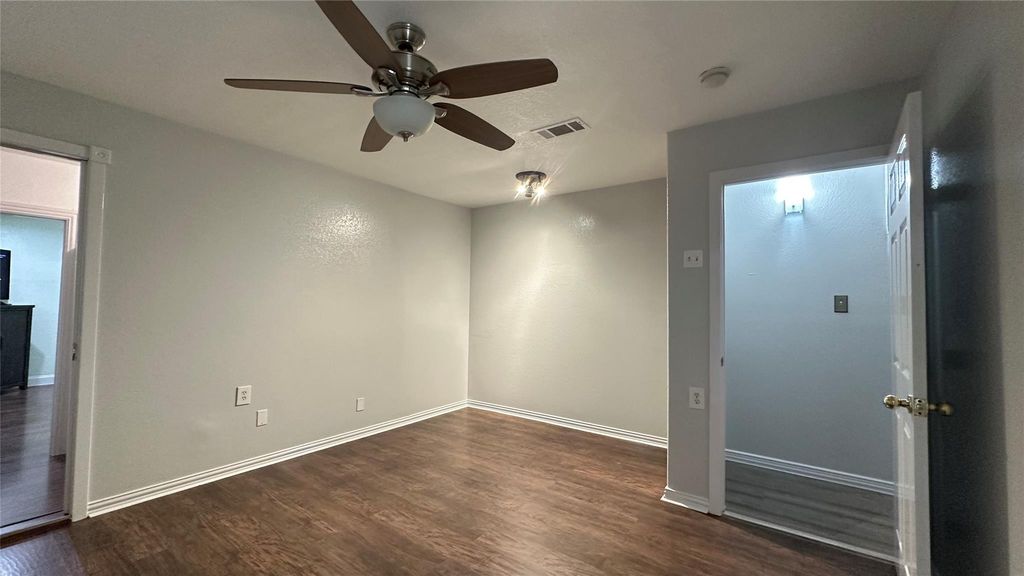 Spare room featuring dark wood-style flooring and ceiling fan