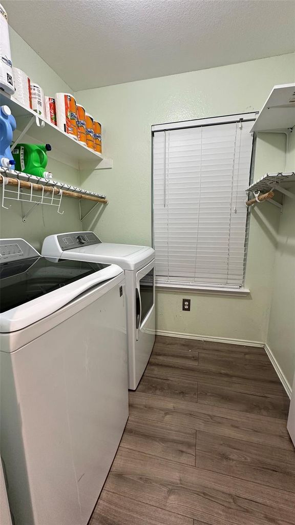 Laundry area with dark wood-type flooring, washing machine and clothes dryer, and a textured ceiling