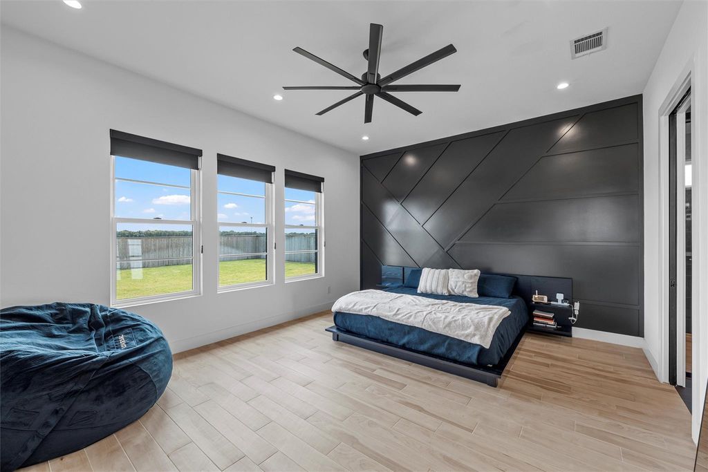 Bedroom with an accent wall, recessed lighting, light wood-style floors, ceiling fan, and a decorative wall