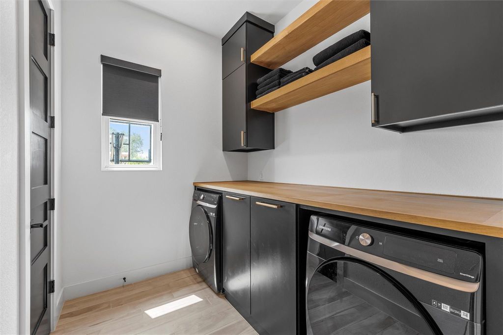Laundry room with light wood-style floors, cabinet space, and washer and clothes dryer