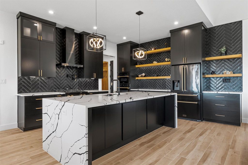 Kitchen with dark cabinets, backsplash, hanging light fixtures, high quality fridge, and light stone countertops