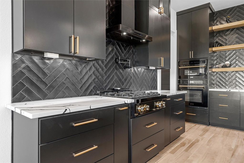 Kitchen with wall chimney exhaust hood, tasteful backsplash, modern cabinets, light stone counters, and stainless steel gas stovetop