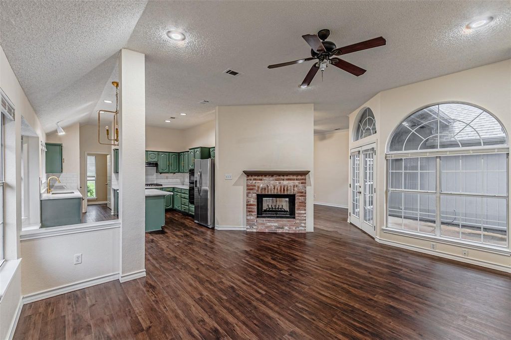 Unfurnished living room featuring a textured ceiling, a fireplace, dark wood-style flooring, a ceiling fan, and recessed lighting