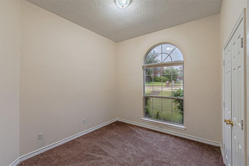 Carpeted empty room with a textured ceiling and baseboards