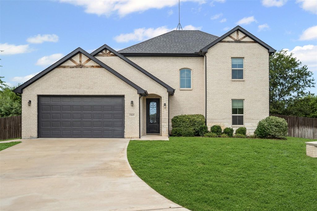View of front of property with an attached garage, brick siding, driveway, and roof with shingles