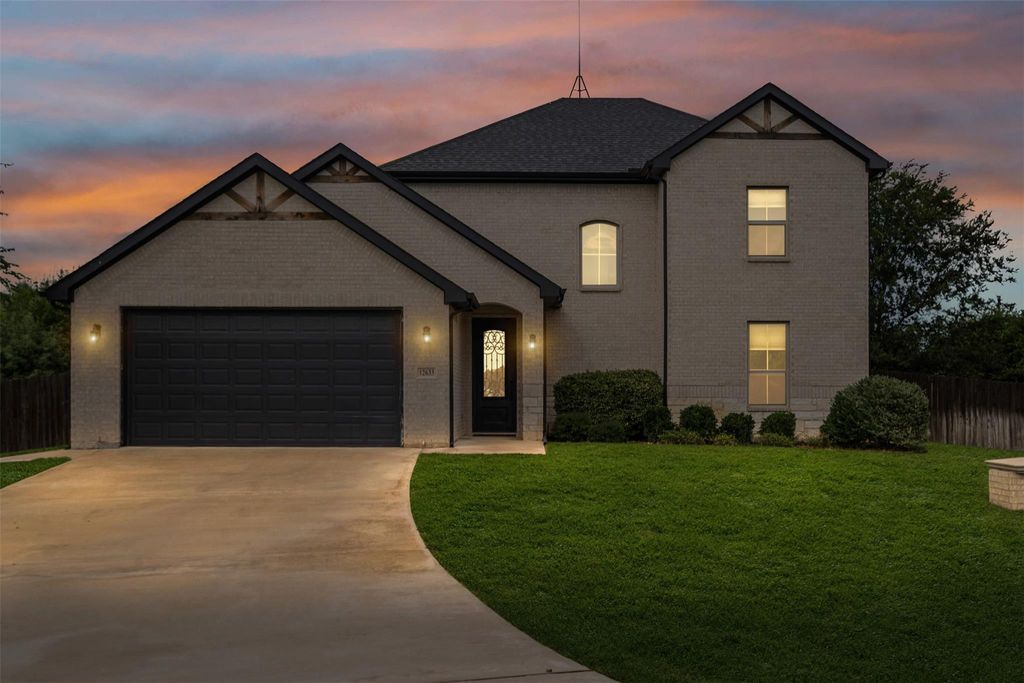 View of front of property with a garage, concrete driveway, and brick siding