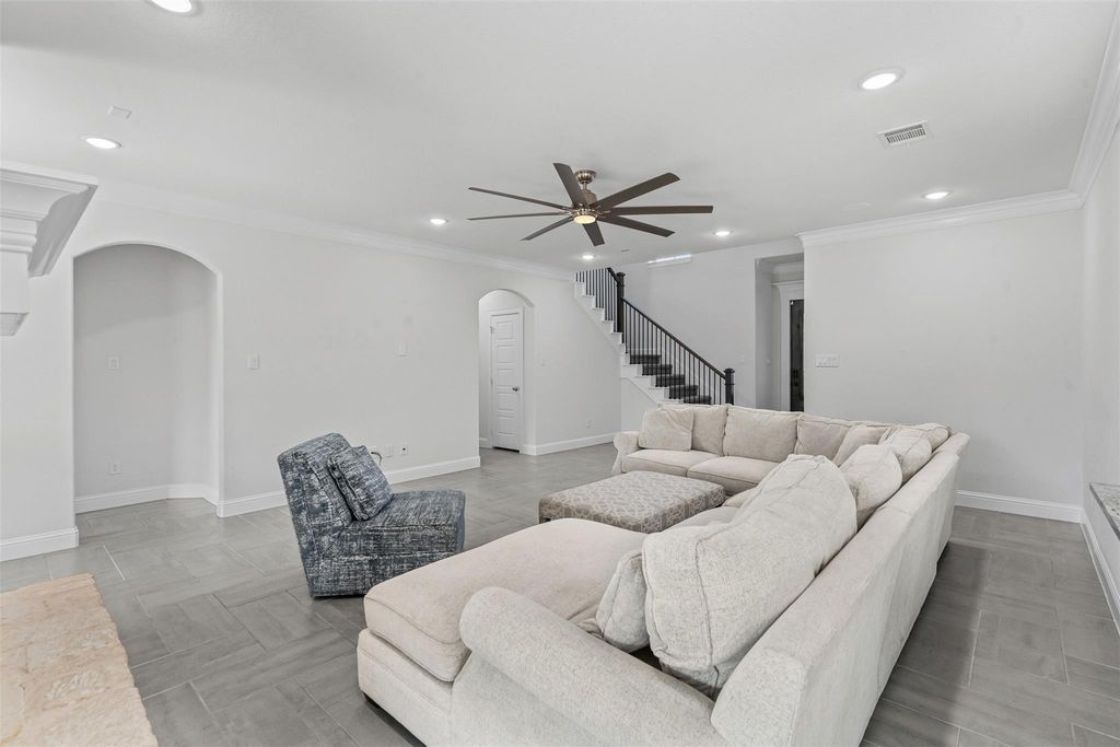 Living area with ornamental molding, recessed lighting, ceiling fan, stairway, and arched walkways