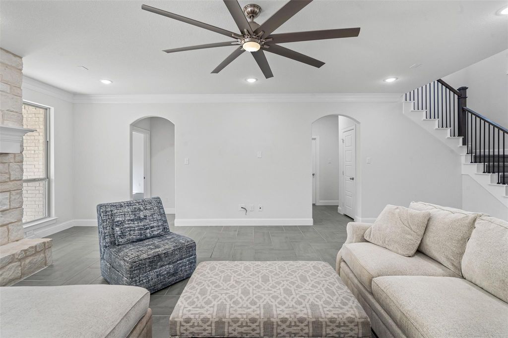 Living room featuring ornamental molding, recessed lighting, stairs, arched walkways, and ceiling fan