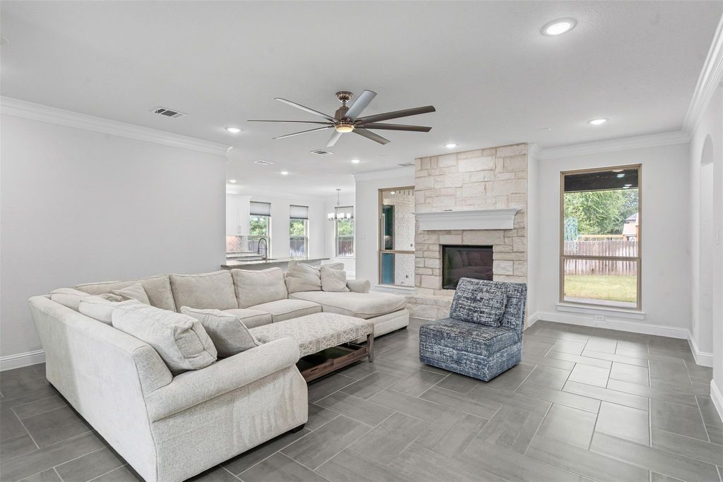 Living area with crown molding, a ceiling fan, a fireplace, and recessed lighting