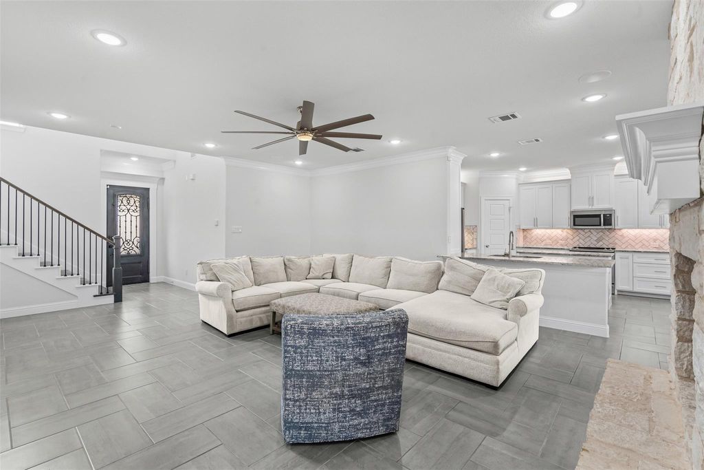 Living room featuring stairway, ceiling fan, ornamental molding, and recessed lighting