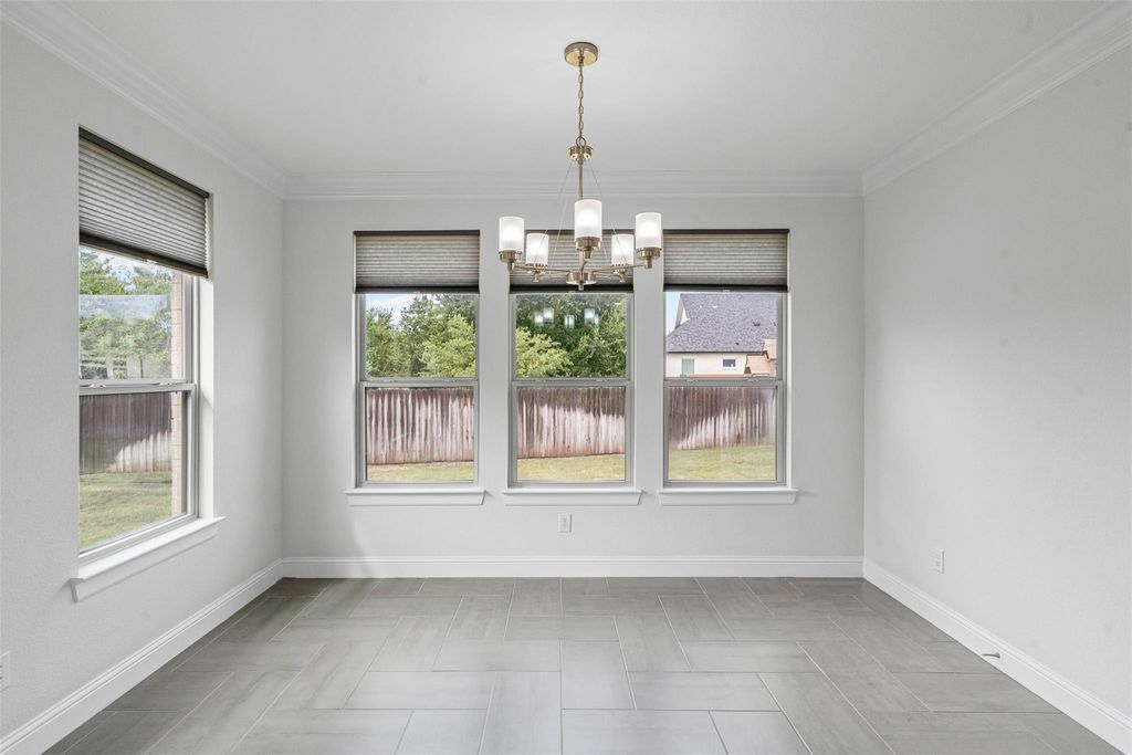 Unfurnished dining area featuring ornamental molding, plenty of natural light, and a chandelier