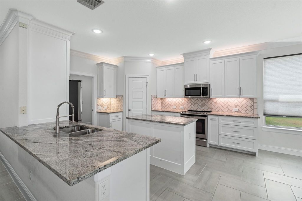 Kitchen with light stone counters, stainless steel appliances, tasteful backsplash, a center island, and a peninsula