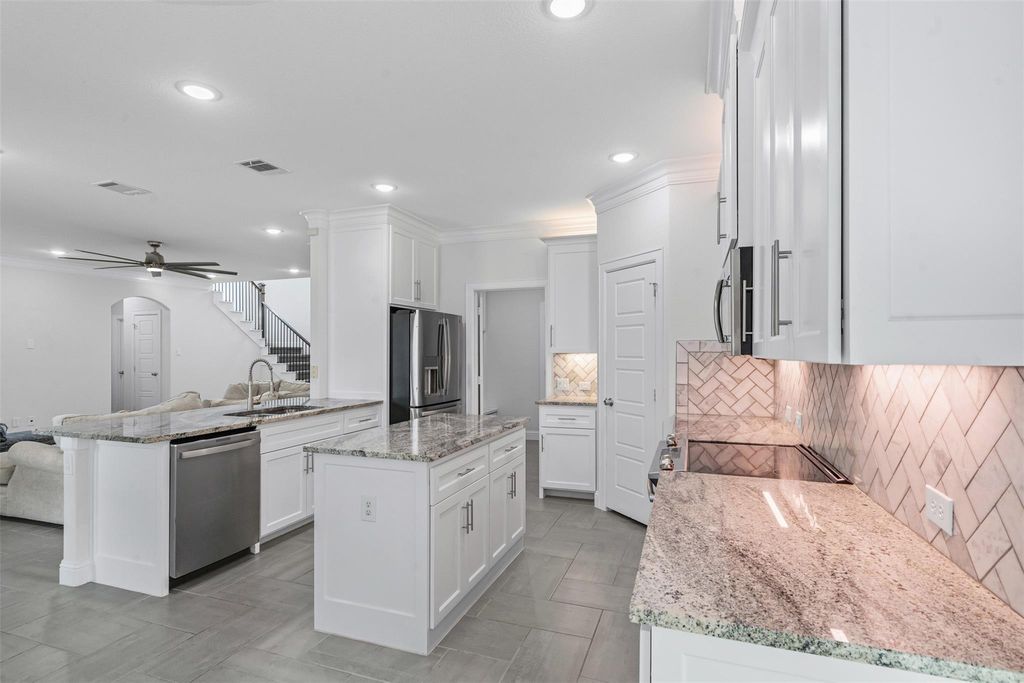 Kitchen with stainless steel appliances, ceiling fan, a peninsula, crown molding, and open floor plan