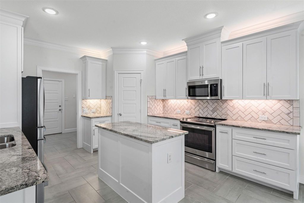 Kitchen with appliances with stainless steel finishes, tasteful backsplash, light stone countertops, crown molding, and recessed lighting