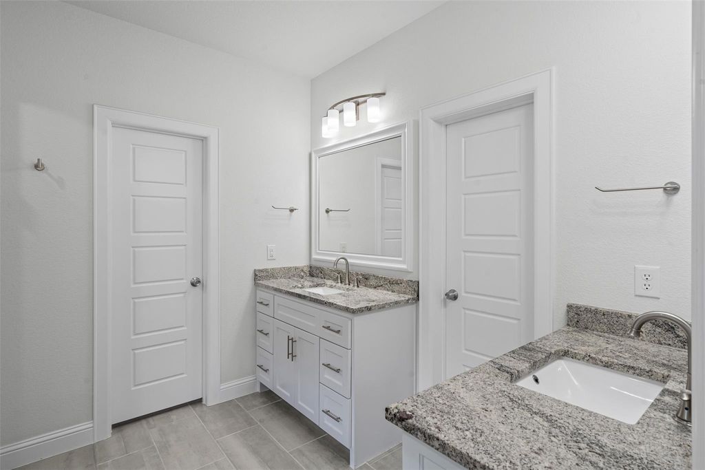 Full bath with two vanities and baseboards