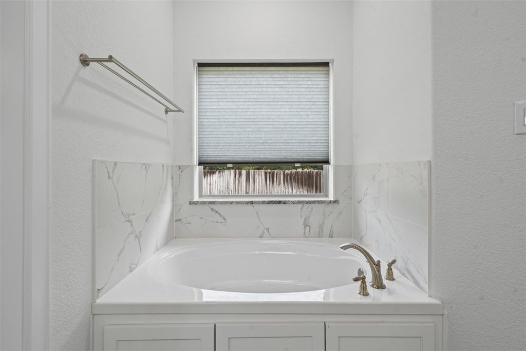 Full bathroom with a textured wall and a bath