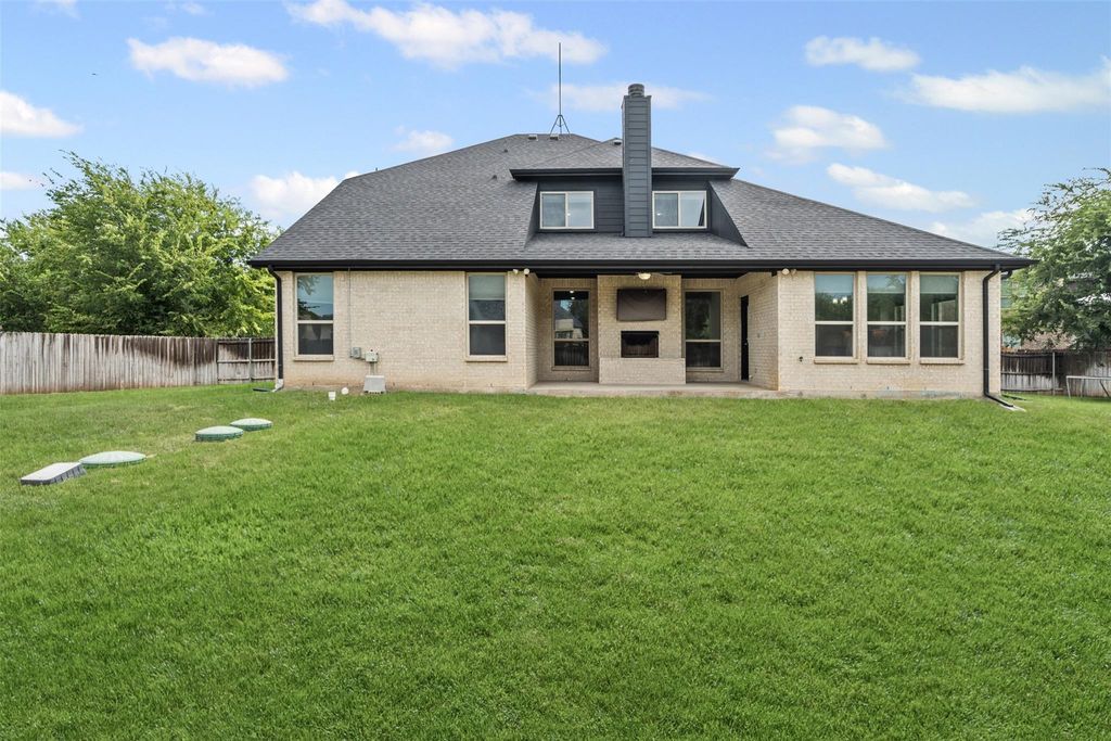 Rear view of property with a fenced backyard, a patio, a chimney, and brick siding