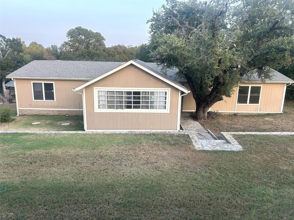 Ranch-style home featuring a front lawn and a shingled roof