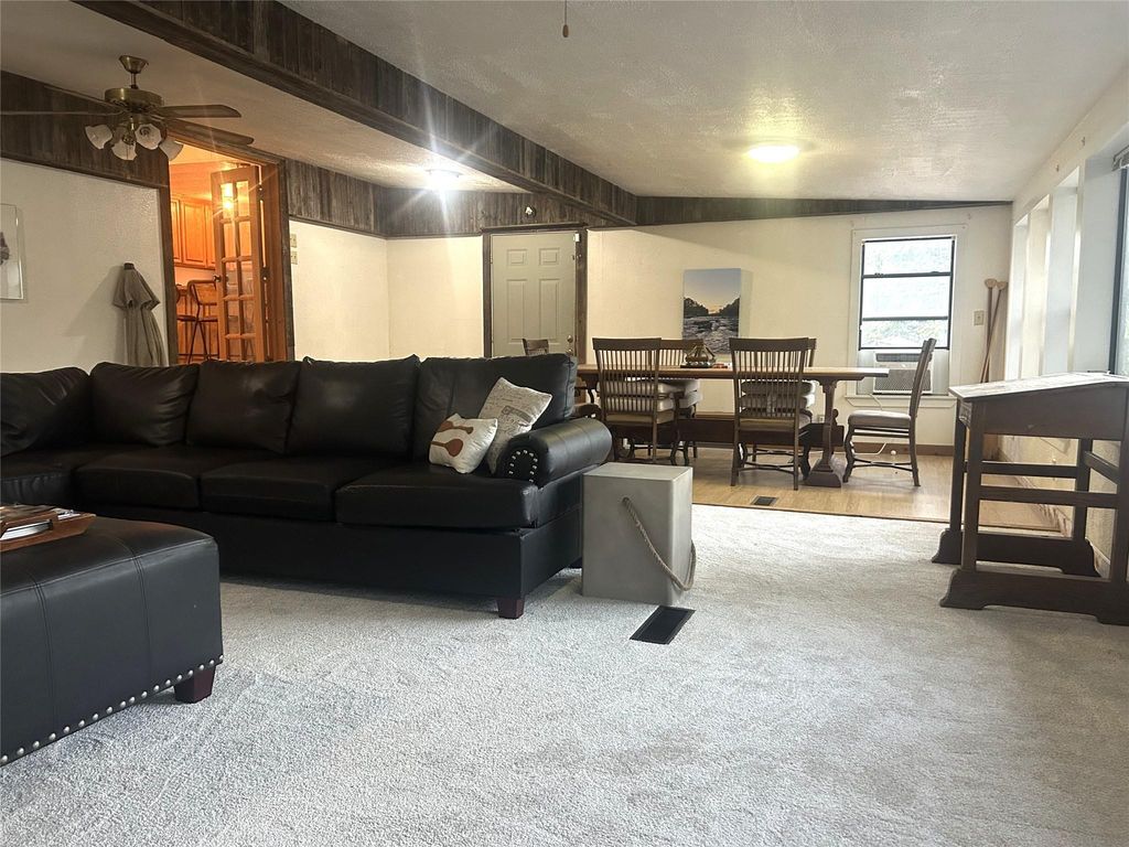 Living room featuring a ceiling fan, light colored carpet, and a textured ceiling
