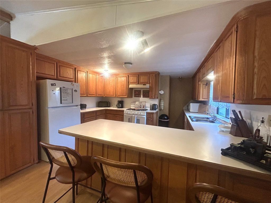 Kitchen featuring light countertops, brown cabinets, white appliances, and a peninsula