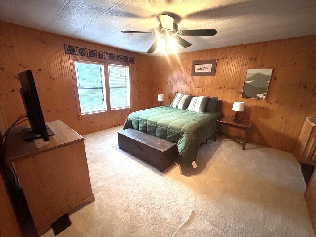 Carpeted bedroom featuring wood walls and ceiling fan
