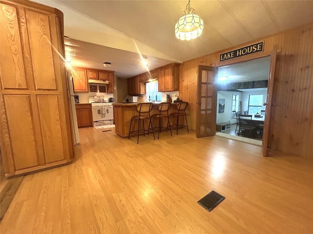 Kitchen with brown cabinetry, a breakfast bar, white appliances, light wood finished floors, and a peninsula