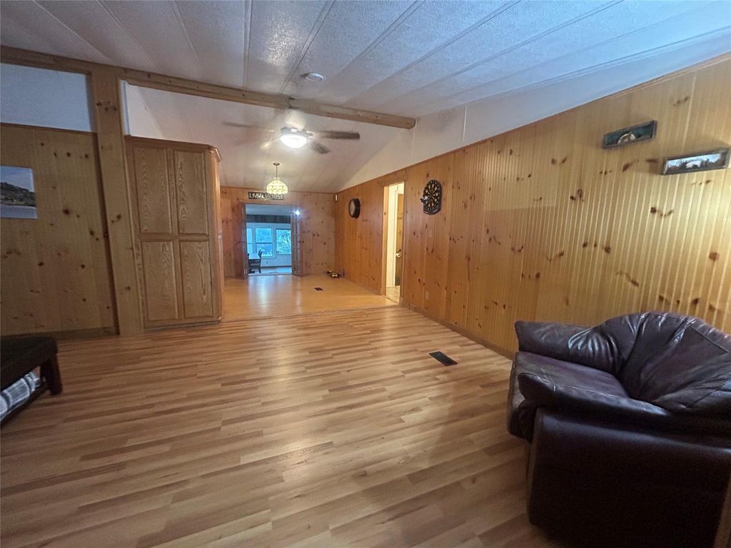 Living room with wood walls, light wood-type flooring, and ceiling fan