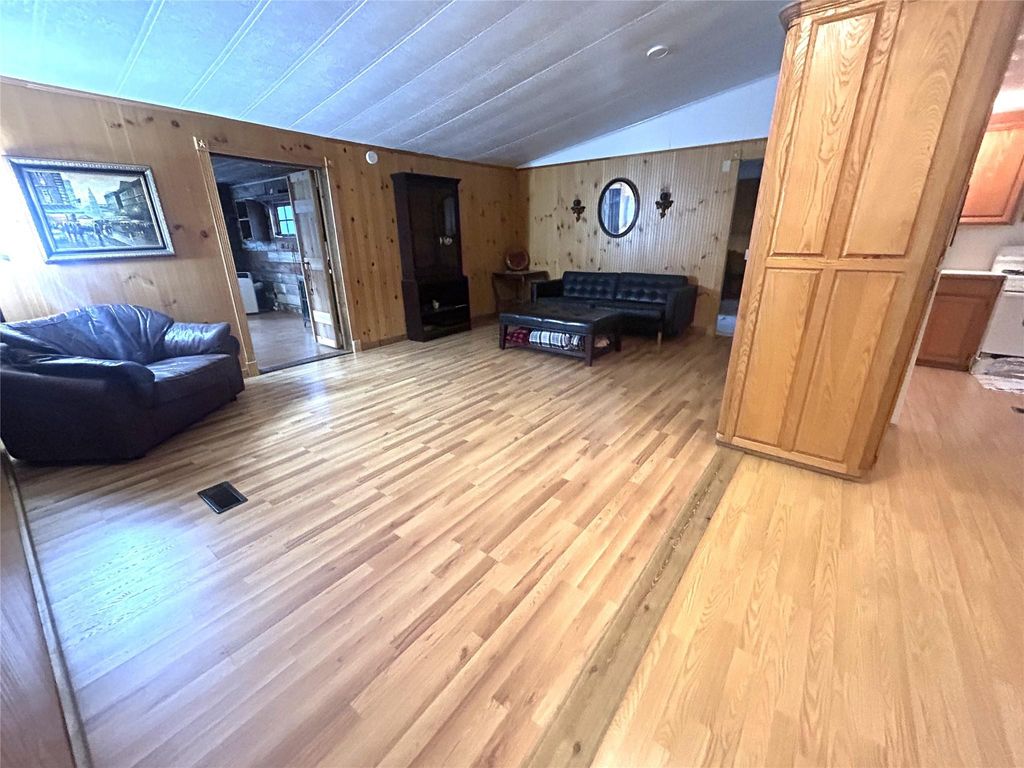 Living room with wood walls, lofted ceiling, and light wood-style flooring