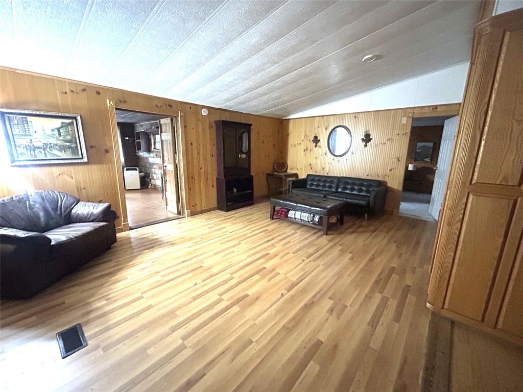 Living room featuring wooden walls, wood finished floors, and vaulted ceiling
