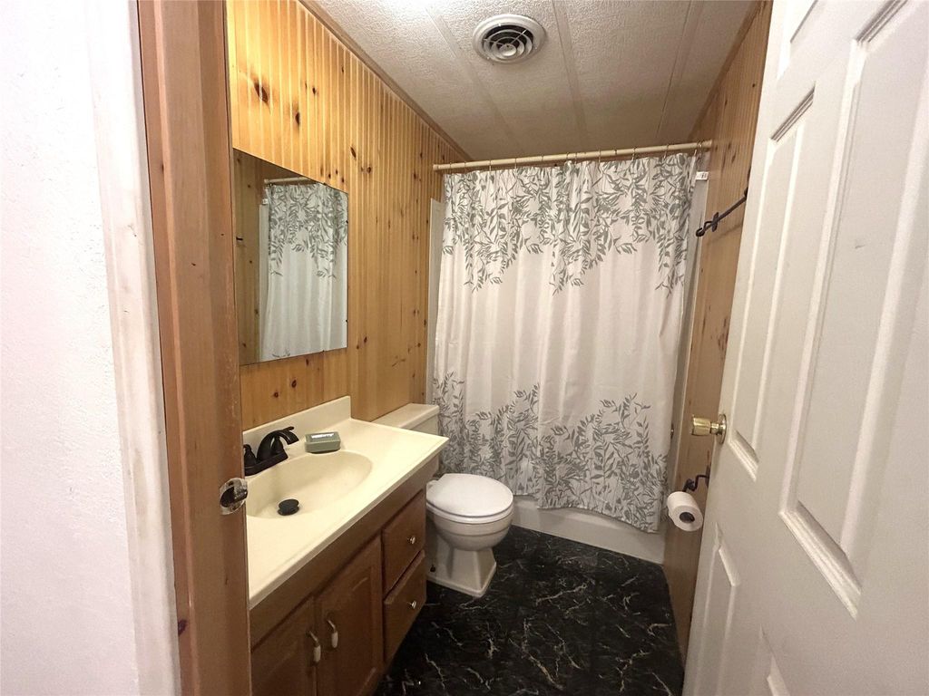 Bathroom featuring wooden walls, vanity, and shower / tub combo with curtain