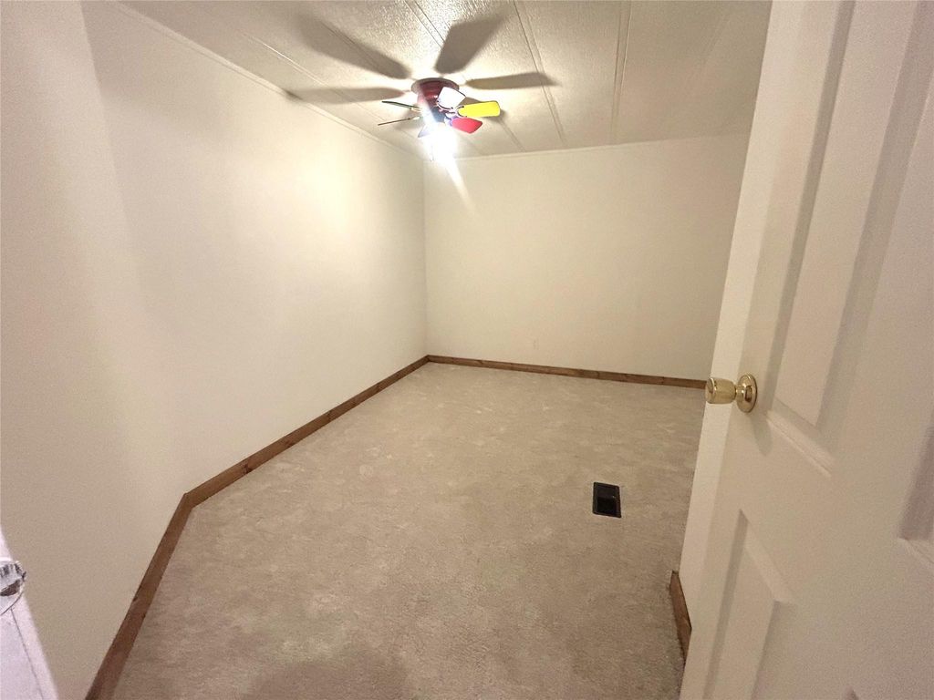 Carpeted spare room with a ceiling fan and a textured ceiling