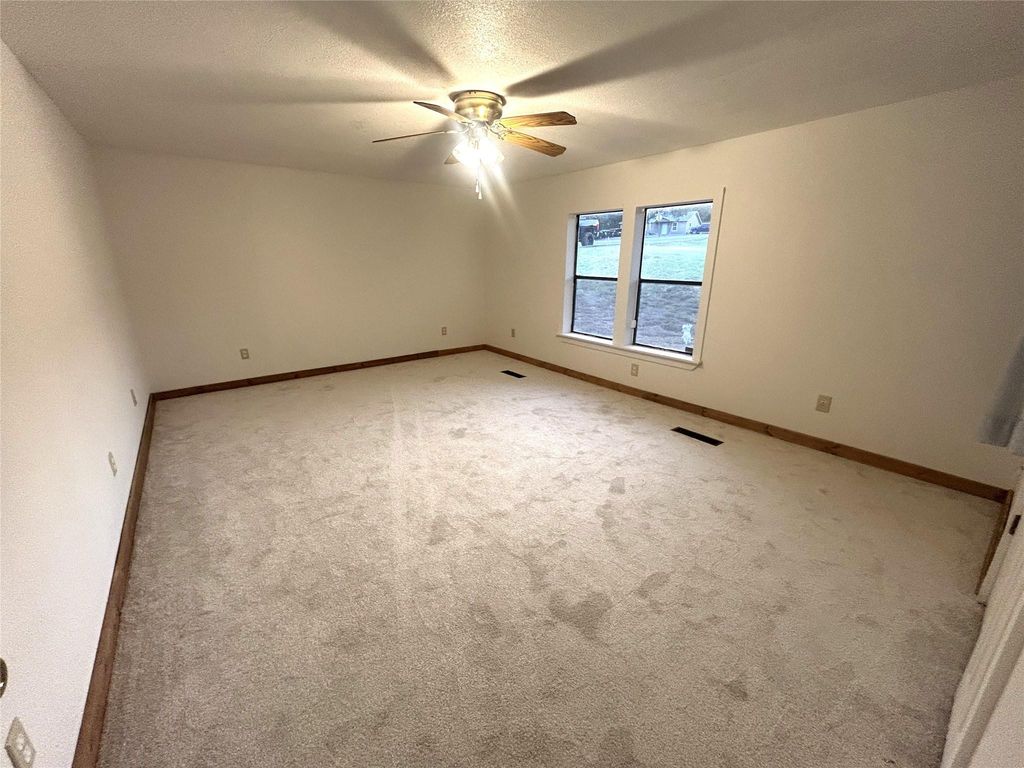 Unfurnished room with a textured ceiling, carpet floors, and ceiling fan