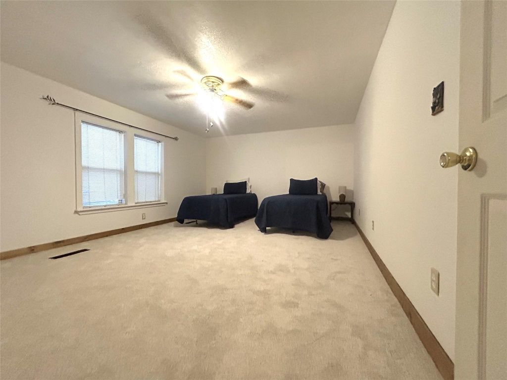 Bedroom featuring light carpet, a ceiling fan, and a textured ceiling