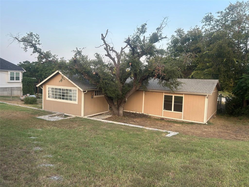 Rear view of property with a yard and roof with shingles
