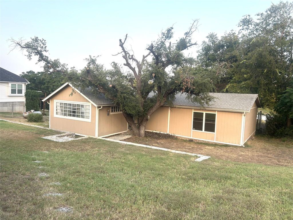 Back of house featuring a lawn and a shingled roof