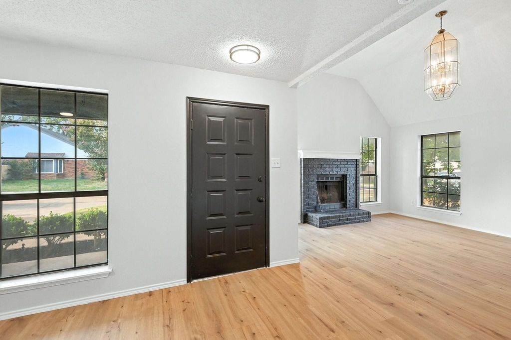 Entrance foyer with light wood-type flooring, a brick fireplace, and a textured ceiling