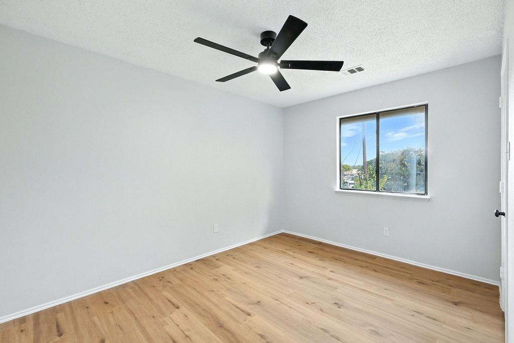 Bedroom with light wood finished floors, a textured ceiling, and ceiling fan