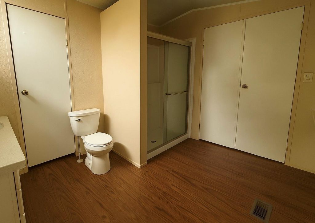 Bathroom featuring a shower stall, dark wood-style flooring, and vanity