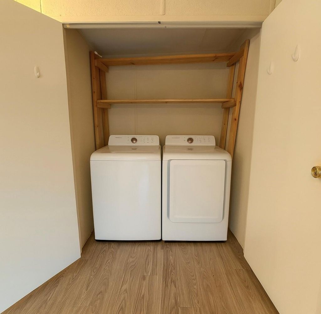 Laundry area with light wood finished floors and washer and clothes dryer